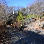 物件南側公道の東側から西方向を撮影。右側石垣の手前が４台分の駐車スペース。